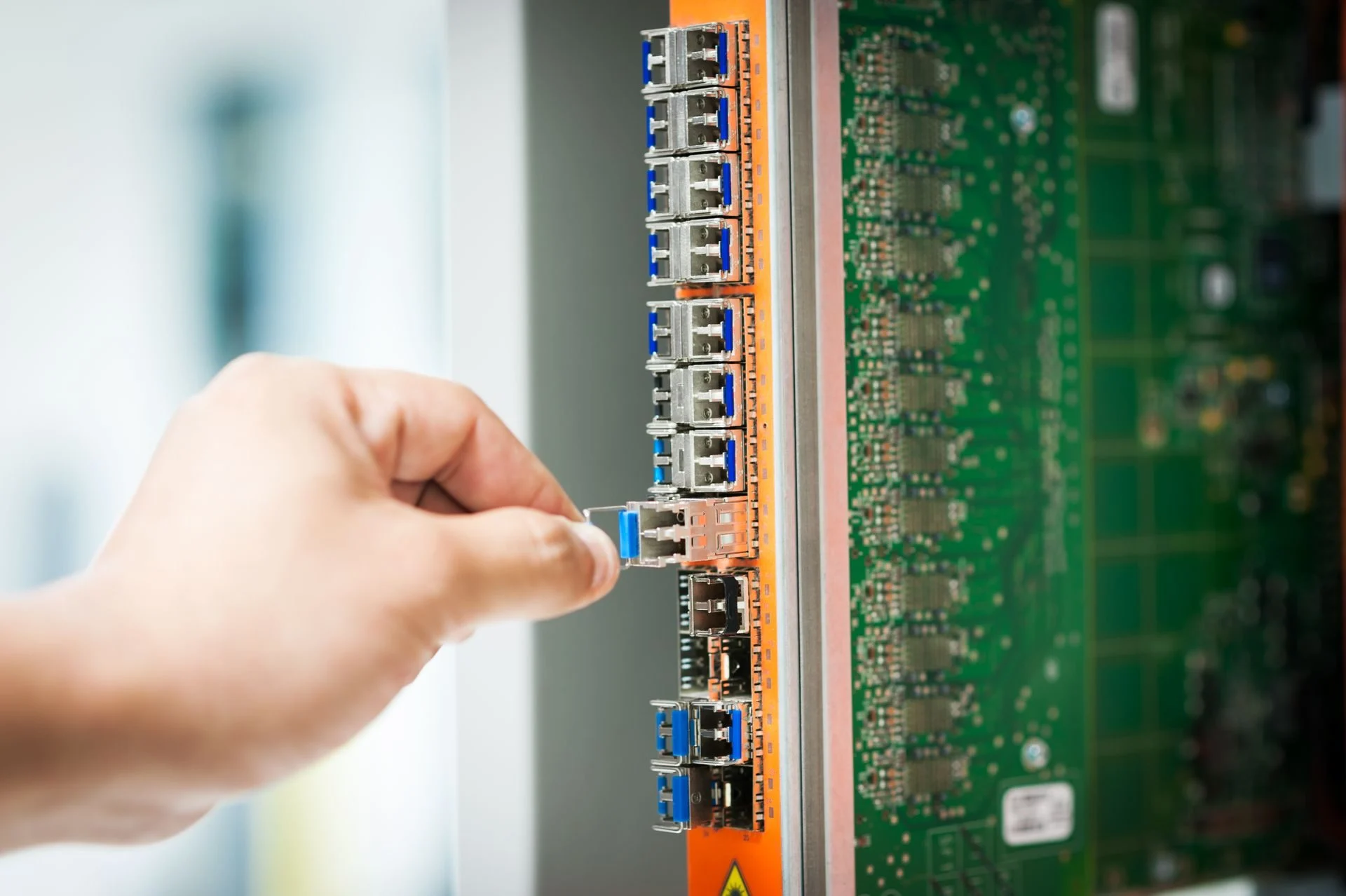 A hand connecting a cable to network equipment