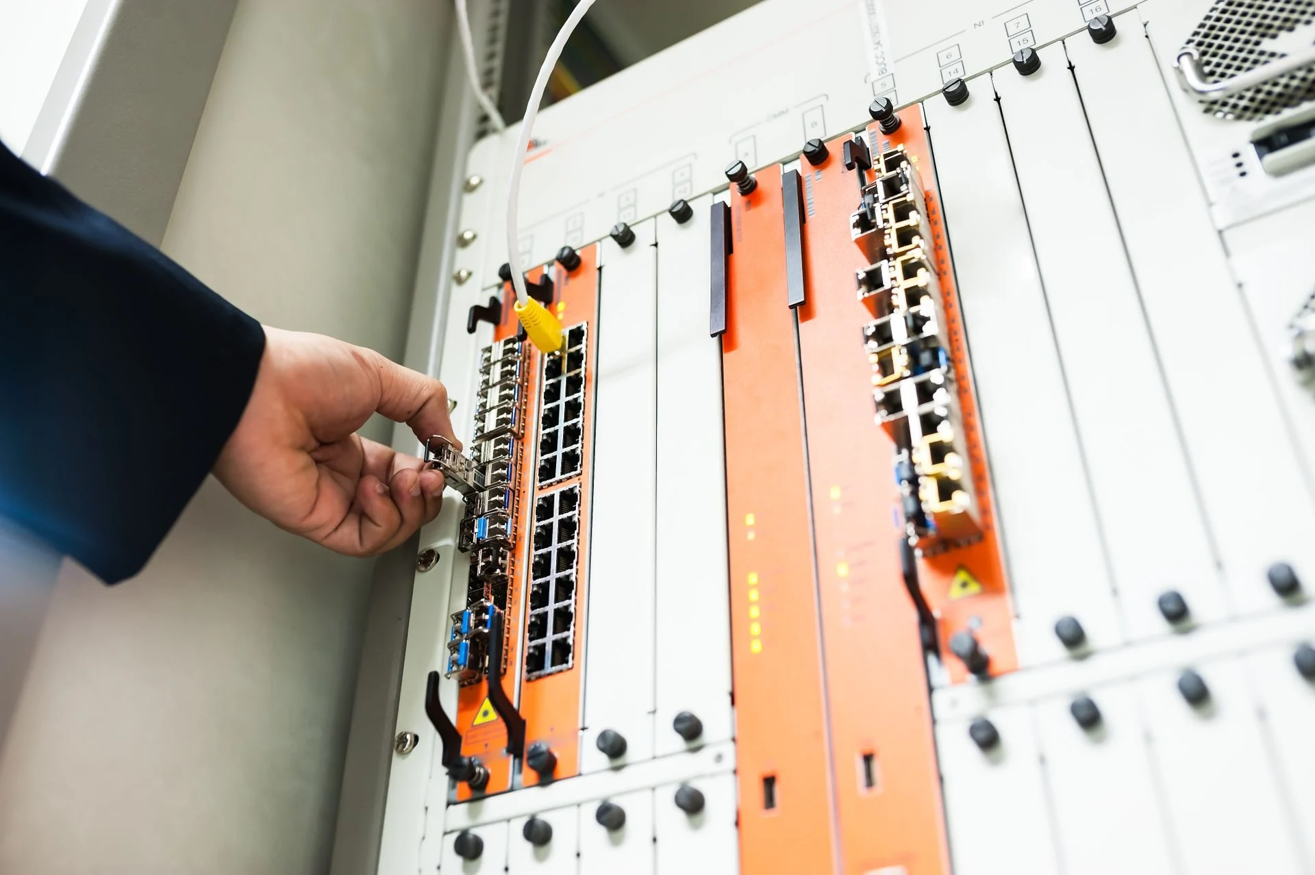 Hands connecting a cable in a network patch panel