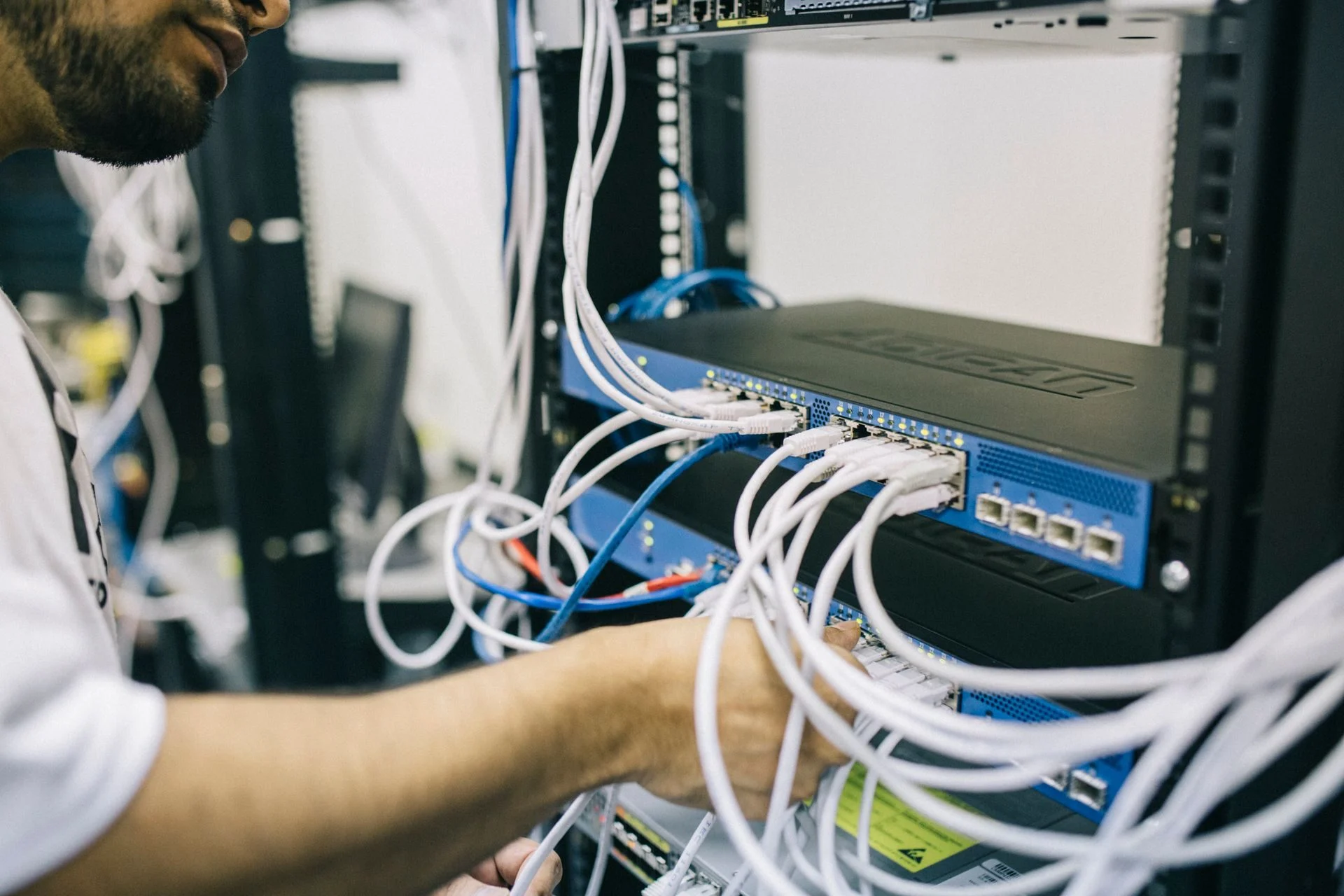 Hands connecting network cables in a server rack